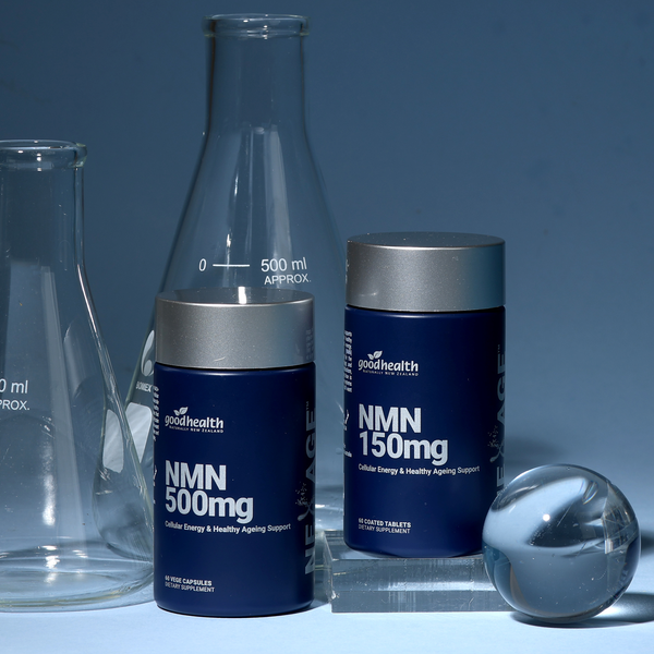 Two GoodHealth supplement bottles labeled NMN 500mg and NMN 150mg with silver caps, styled with glass laboratory equipment and a reflective sphere against a blue background.